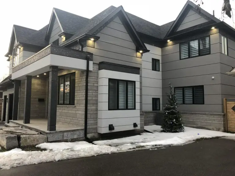 Grey house with horizontal panel lines and a light surround framing a ground-floor window