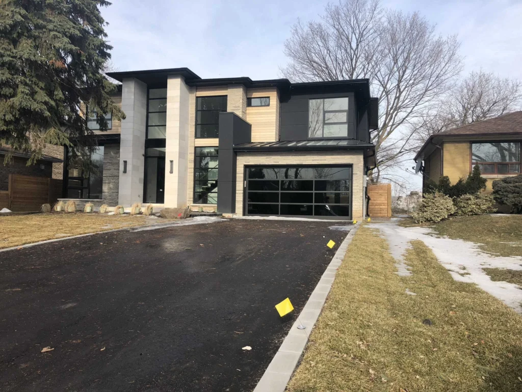Contemporary house with light stucco columns, stone and wood accents and a glass garage door