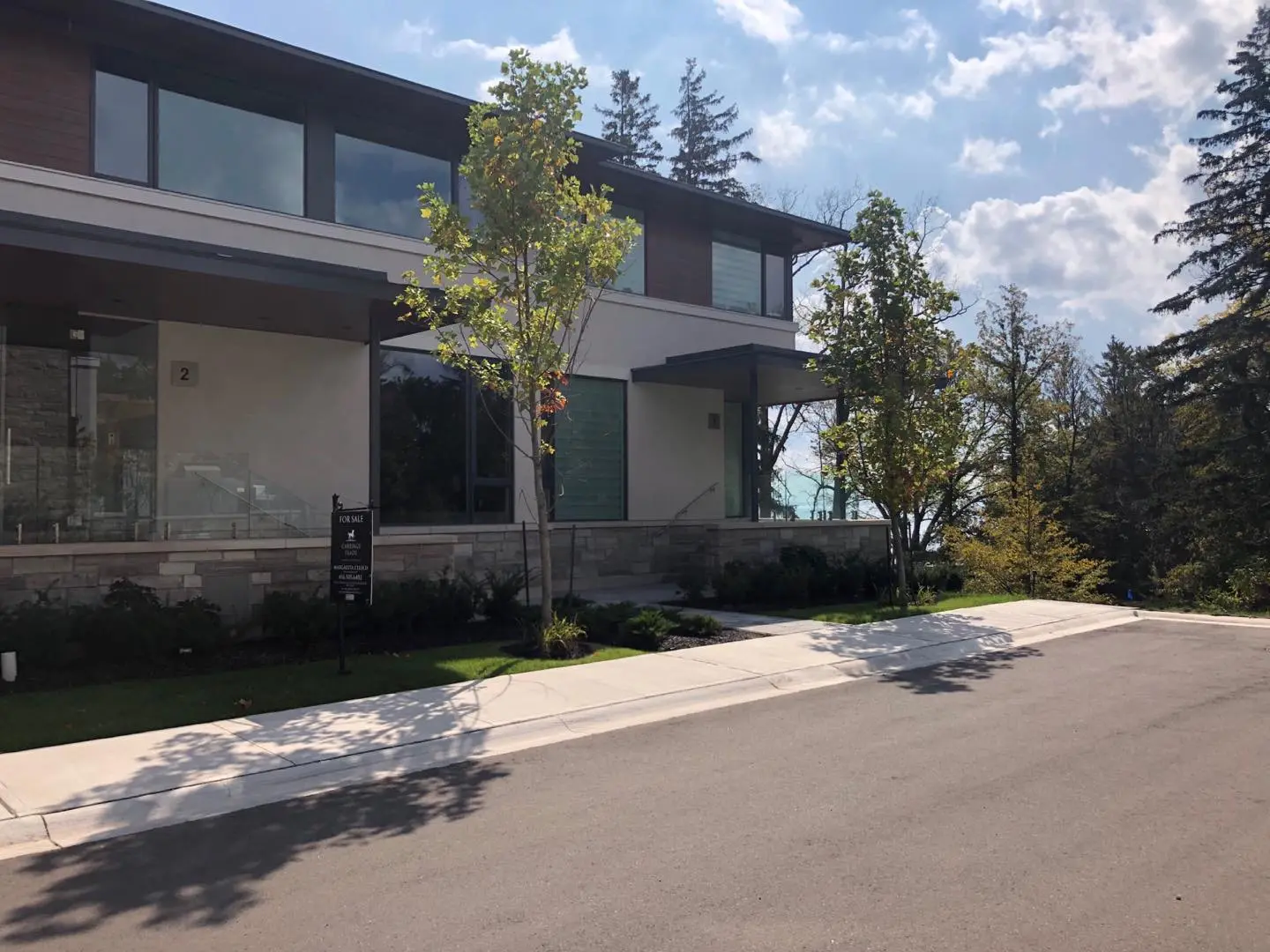 Modern two-storey house with a stone base, wood-look panels and large windows facing the street