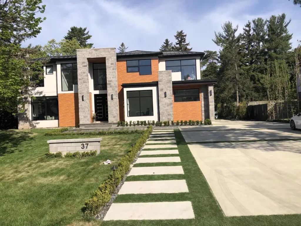 Finished modern house with white stucco, stone piers and new landscaping