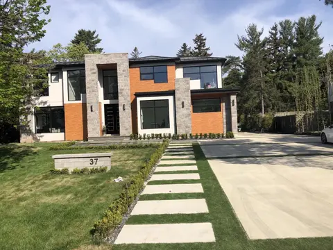 Modern house with light stucco, stone columns and orange accent panels