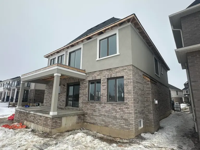 Grey stucco upper storey above a brick ground floor on a new house in snow