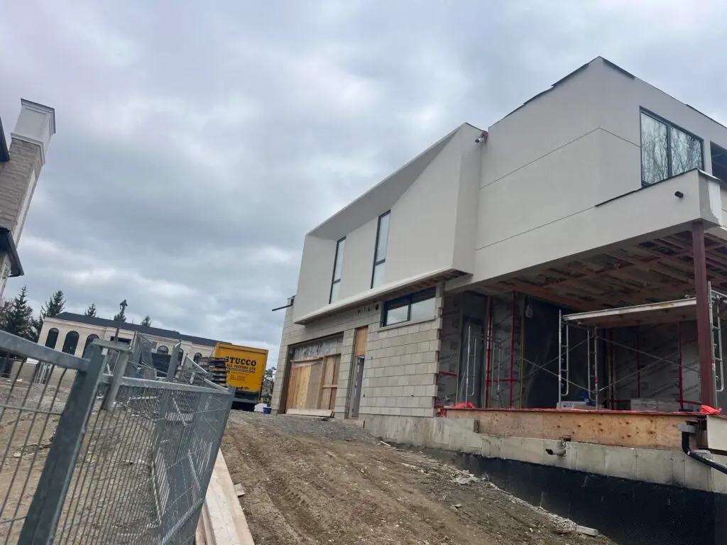 Modern house with a light stucco upper floor and scaffolding under the overhang