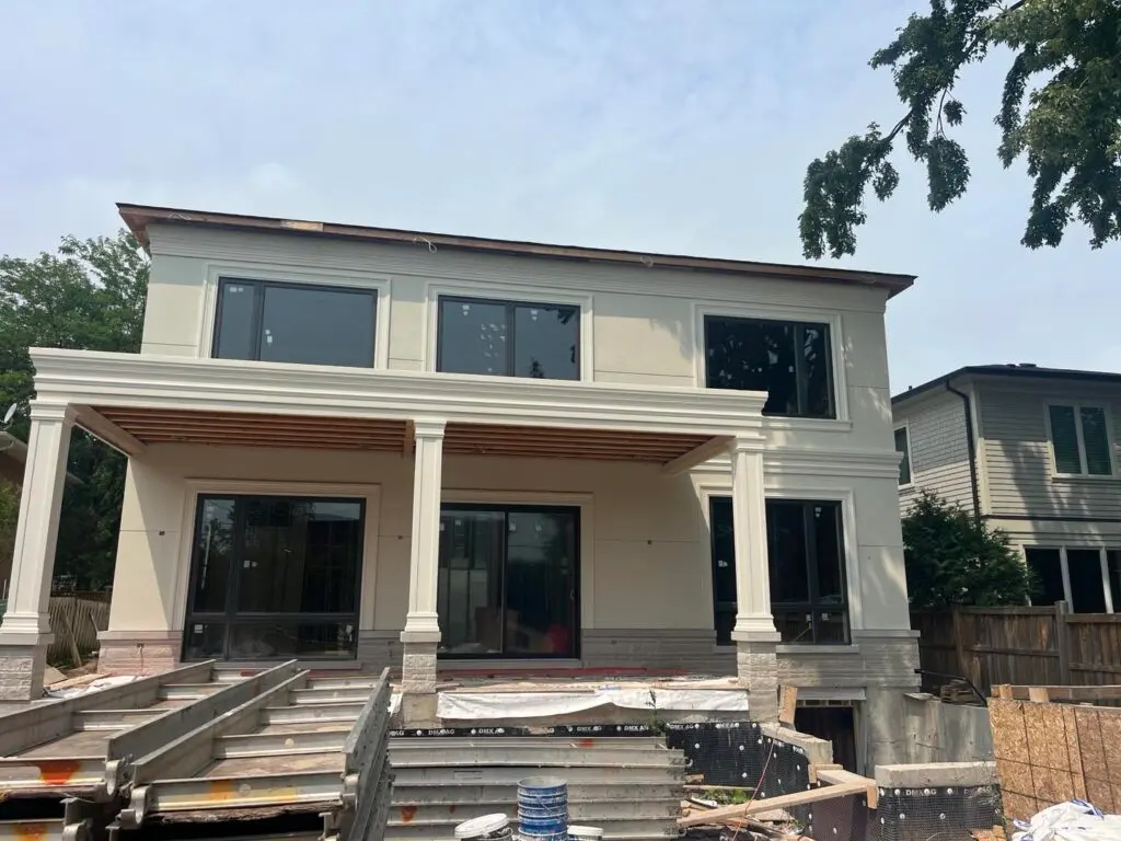 Cream stucco on a two-storey house with columns, porch ceiling still open and steps not yet built