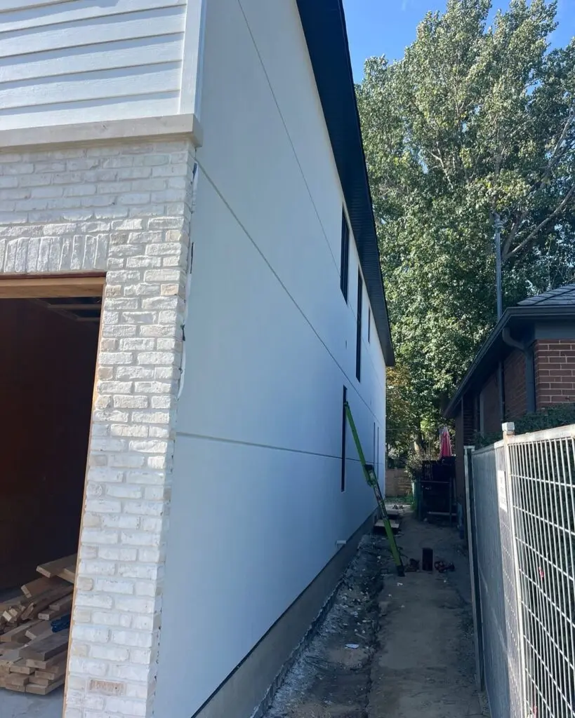 Narrow side yard between a white painted brick wall and a smooth white wall